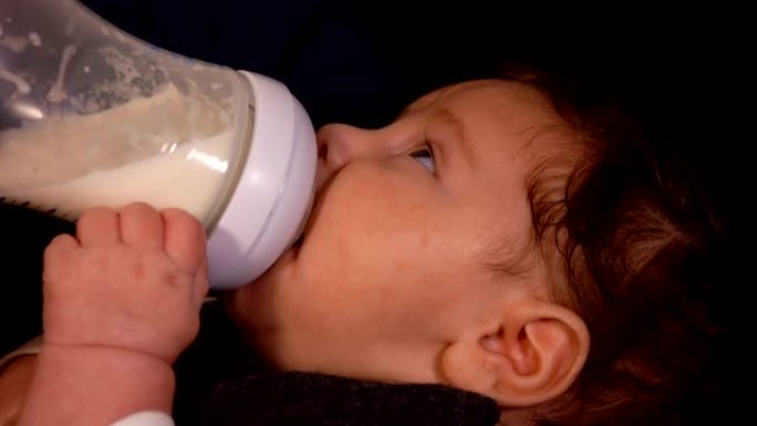 可爱的小婴儿在母亲的怀抱中奶瓶喂养