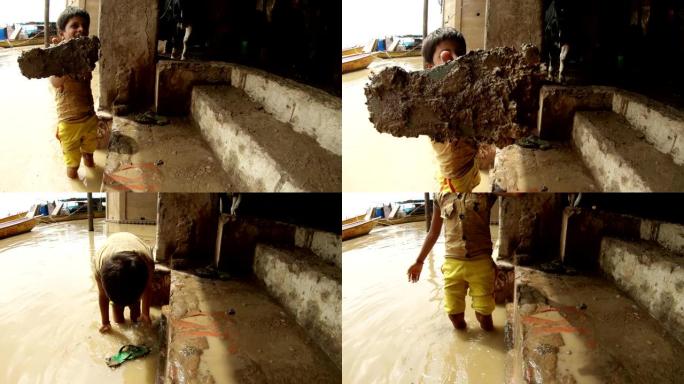 印度小男孩展示了涂有牛屎的拖鞋，并在圣河恒河的脏水中清洗了它，微笑着贝托楼梯蹄子船瓦拉纳西
