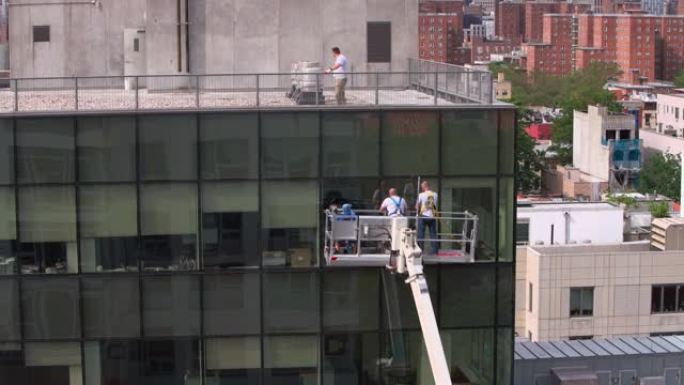 高空作业。两队蓝领工人检查办公楼玻璃立面: 一队从外面使用升降平台，另一队从里面。
