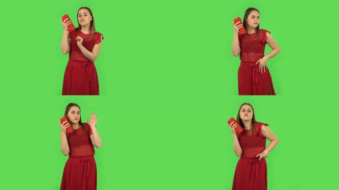 穿着红色连衣裙的温柔女孩正在用蓝牙便携式扬声器听音乐并跳舞。绿屏