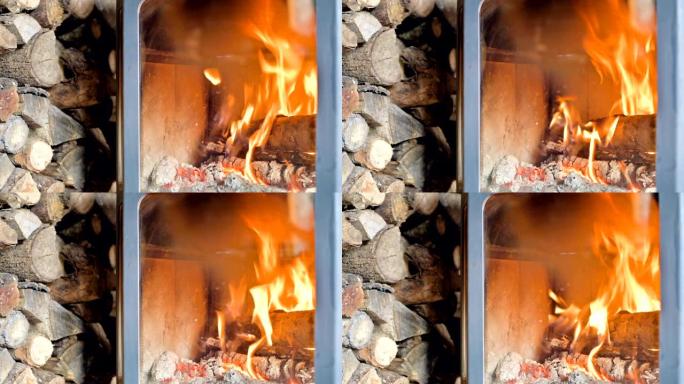 白天在耐火玻璃后面的自制现代炉灶中燃烧柴火的特写镜头，旁边是一大堆柴火。环保能源
