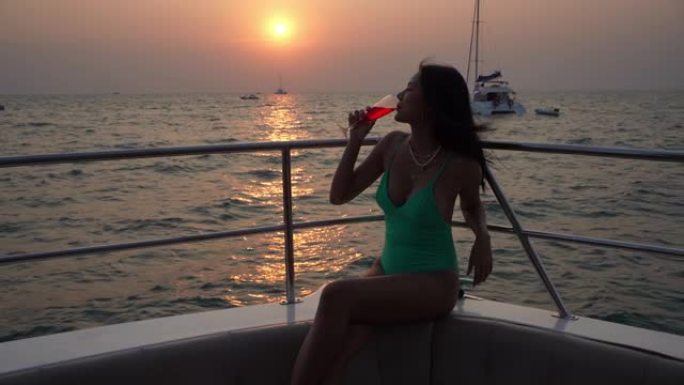 亚洲女士在游艇上享受和喝鸡尾酒。