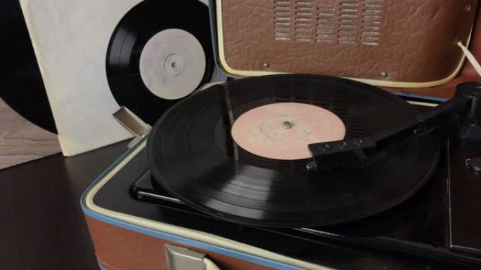 黑胶唱片在唱机的光盘上旋转。播放结束时拾音器头上升。一个人把皮卡放在架子上。