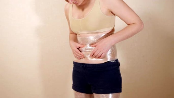 年轻女子用保鲜膜包裹胃
