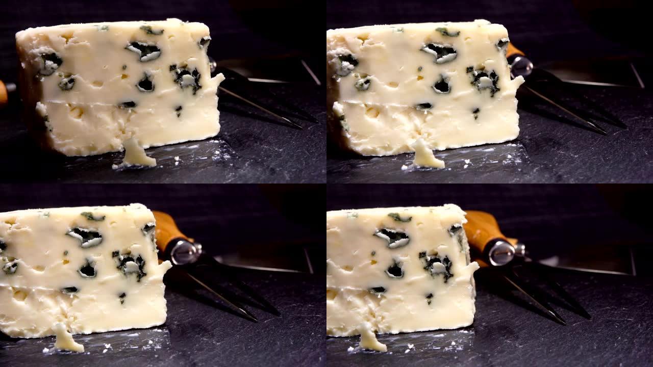 从黑石板上切下并提起一块蓝模奶酪