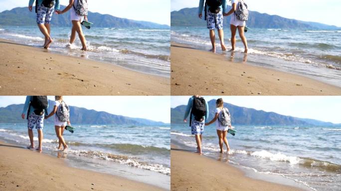 年轻夫妇在海洋背景下沿着海滩走。一对带着背包的旅行者在海边行走，泼水洗脚。男人和女人在海浪的沙滩上漫