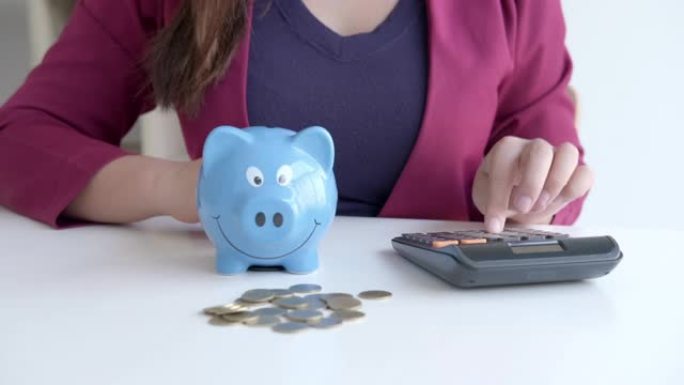 4k视频片段，女人将硬币放入存钱罐，硬币堆并用计算器计算以节省资金计划未来