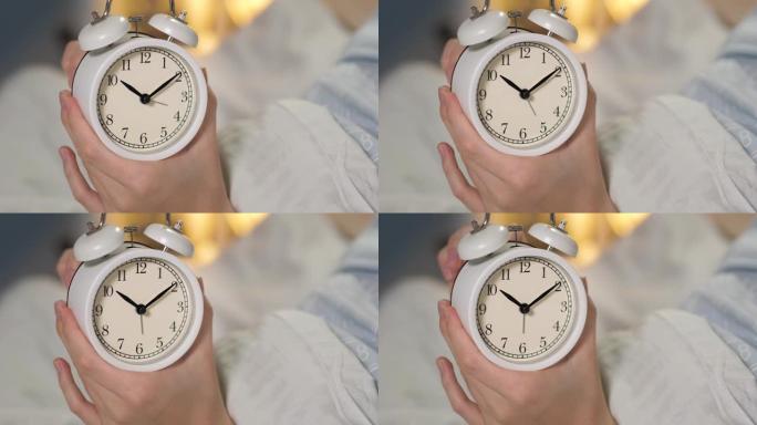 女性双手握着闹钟，并设置小手六个小时。特写
