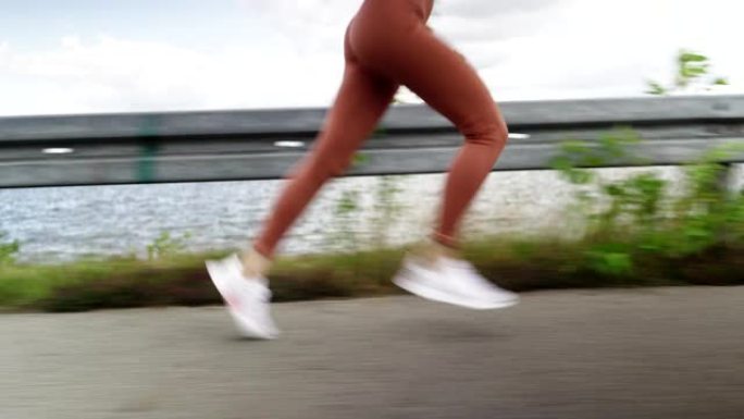 在湖附近的乡间小路上奔跑时，女性腿的侧面跟踪镜头