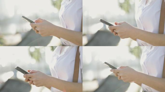身穿白衬衫的亚洲女商人正在使用智能手机在公园外的社交媒体上发短信分享消息。