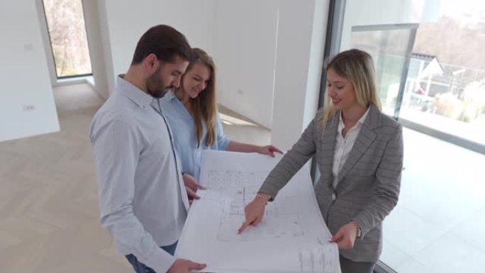 一位年轻的建筑师向一对年轻夫妇展示了他们新房子的蓝图。