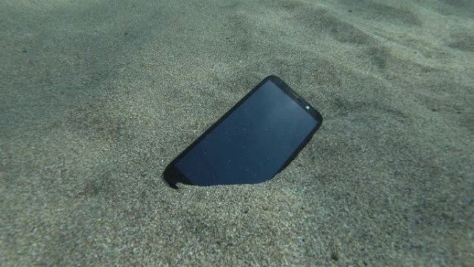 智能手机位于屏幕上的洞穴海床上，用小波反射蓝色的水面。水下视图。地中海，欧洲。