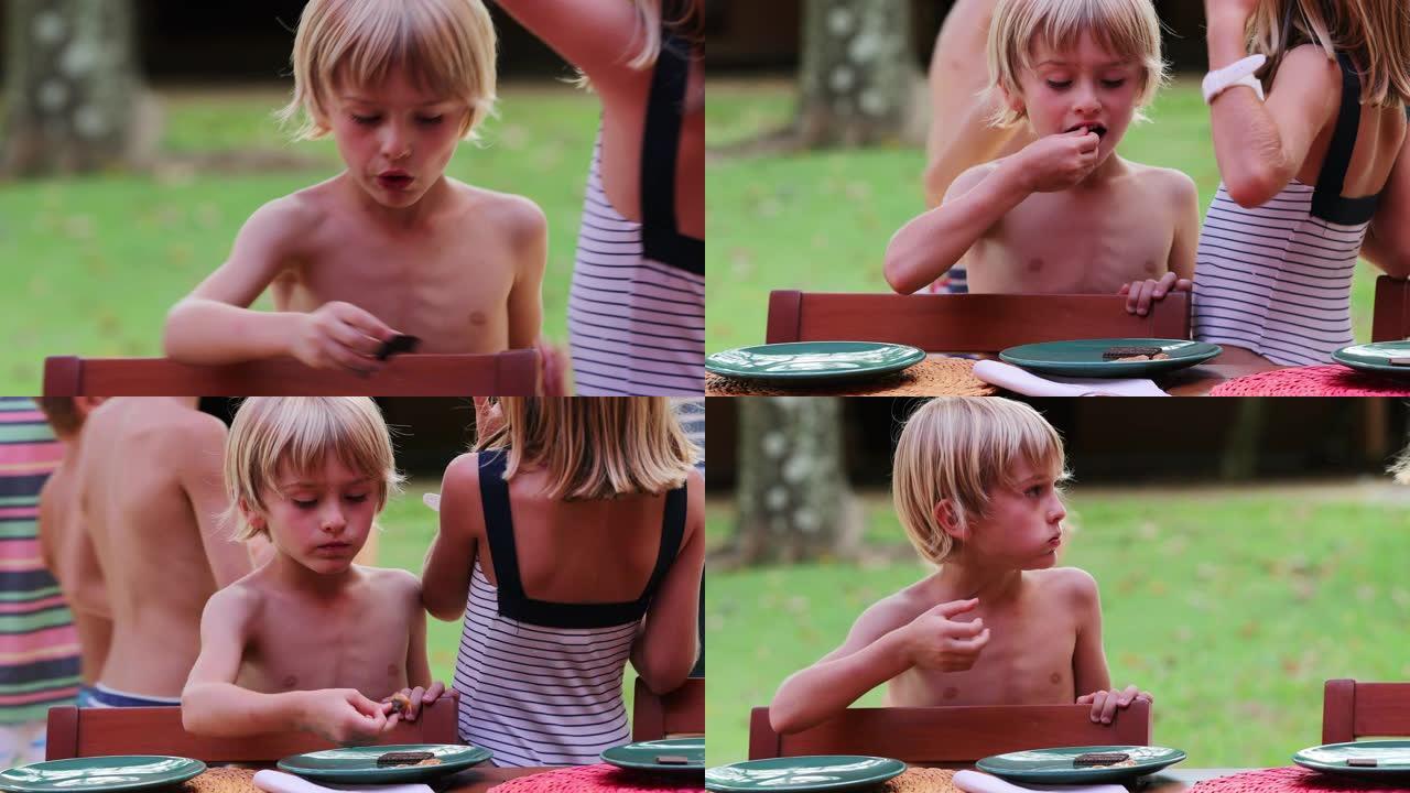 英俊的金发小男孩吃饼干坦率和现实生活中的家庭场景，背景是孩子