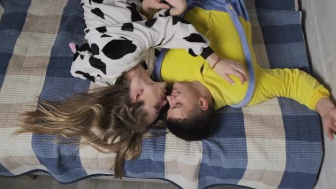 床上的年轻夫妇互相拥抱。穿着睡衣躺在床上的男人和女人