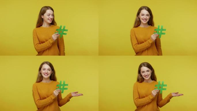 微笑的女孩有着友好和善的面部表情，拿着绿色的hash标志，举起手掌展示拷贝空间，
