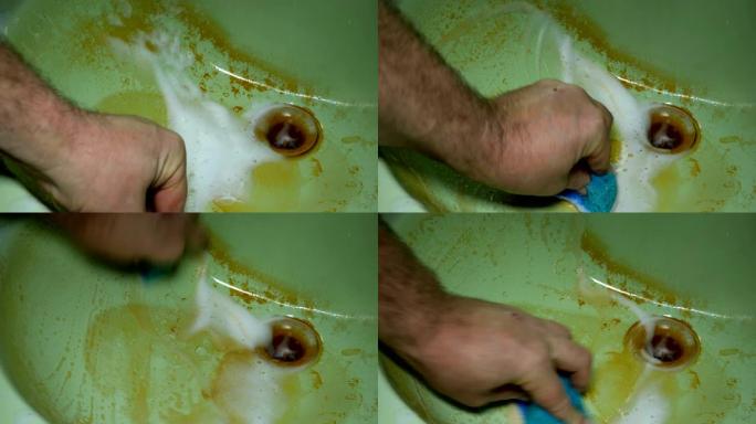 人用泡沫和海绵洗手并清洁生锈的脏水槽。