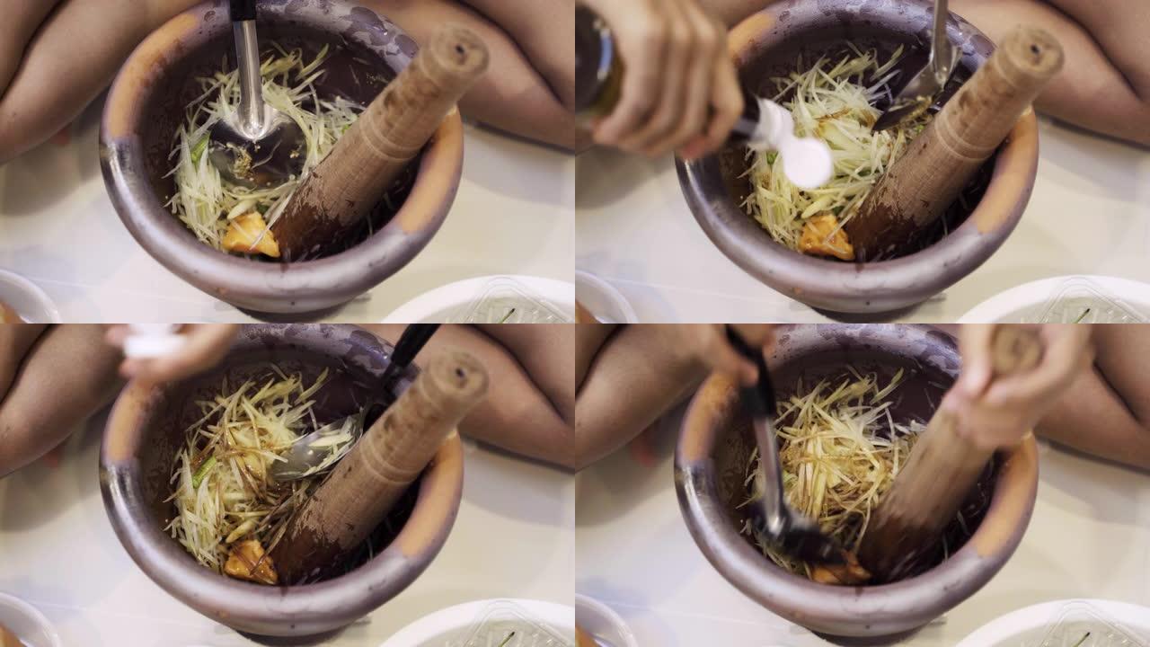 特写女人的手用杵烹饪辛辣的Somtam，SomTum或泰国木瓜沙拉一种著名的泰国饮食和健康的砂浆。健