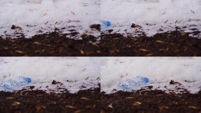 用过的塑料瓶在融化的雪附近的地面上的特写镜头。