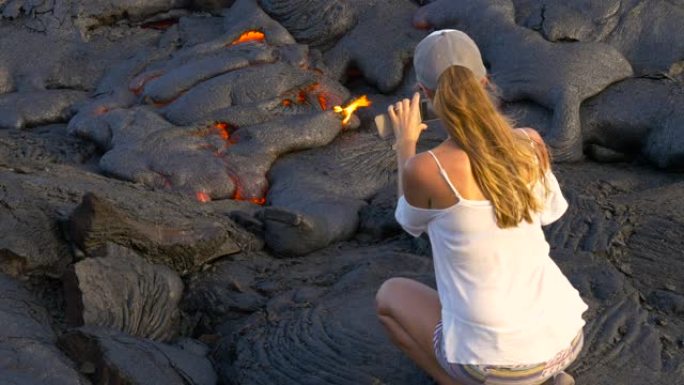 在夏威夷基拉韦厄火山与熔岩合影的徒步旅行女孩