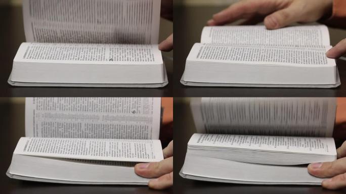 桌子上有一本开放的圣经。一个人慢慢地翻阅页面寻找所需的章节。特写镜头。