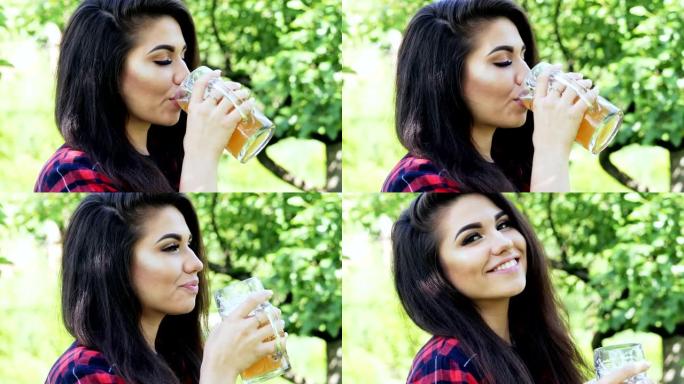 年轻幸福的女人的肖像在花园里喝杯啤酒，止渴