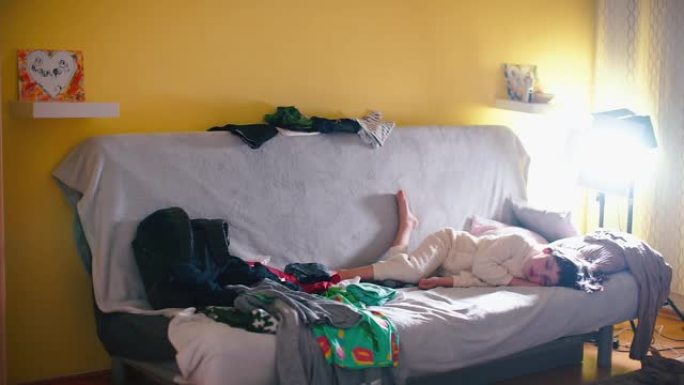 男孩睡在家里的沙发上。散落的衣服周围。