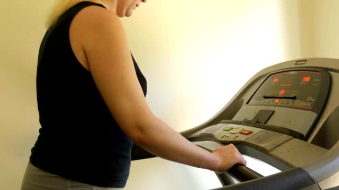 一个穿着运动服的无名胖女人在家跑步机上锻炼