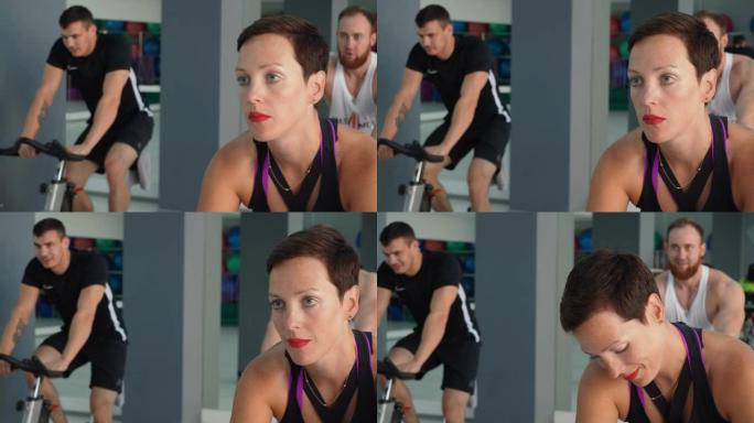美女在健身房骑自行车课训练。肖像健身女性在自行车健身房的室内自行车上训练。运动女子在集体训练中锻炼自