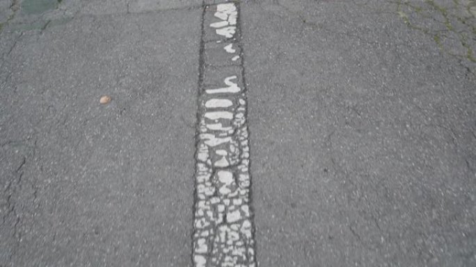 破旧的白色箭头在破裂的旧灰色沥青上。运动方向的道路标记