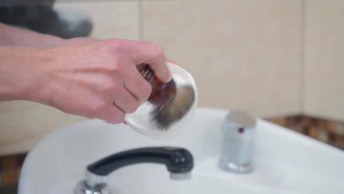 造型师在白色盥洗台上方用刷子准备剃须泡沫，近距离拍摄。记录在美发沙龙。理发店内部。