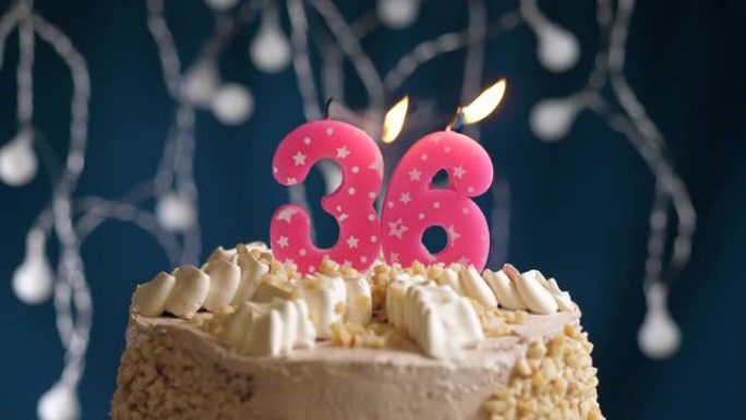 蓝色背景上有36号粉色蜡烛的生日蛋糕。蜡烛吹灭了。慢动作和特写视图