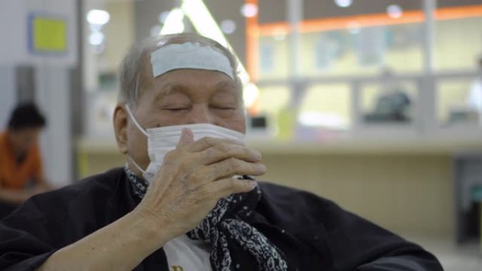 资深亚裔男子戴口罩在医院等候时咳嗽