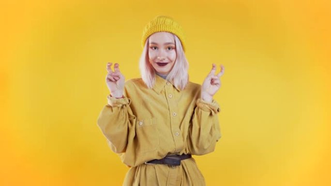 漂亮的朋克女孩用手和两个手指像引号一样展示，弯曲手指孤立在黄色背景上。非常有趣，讽刺和讽刺的概念。