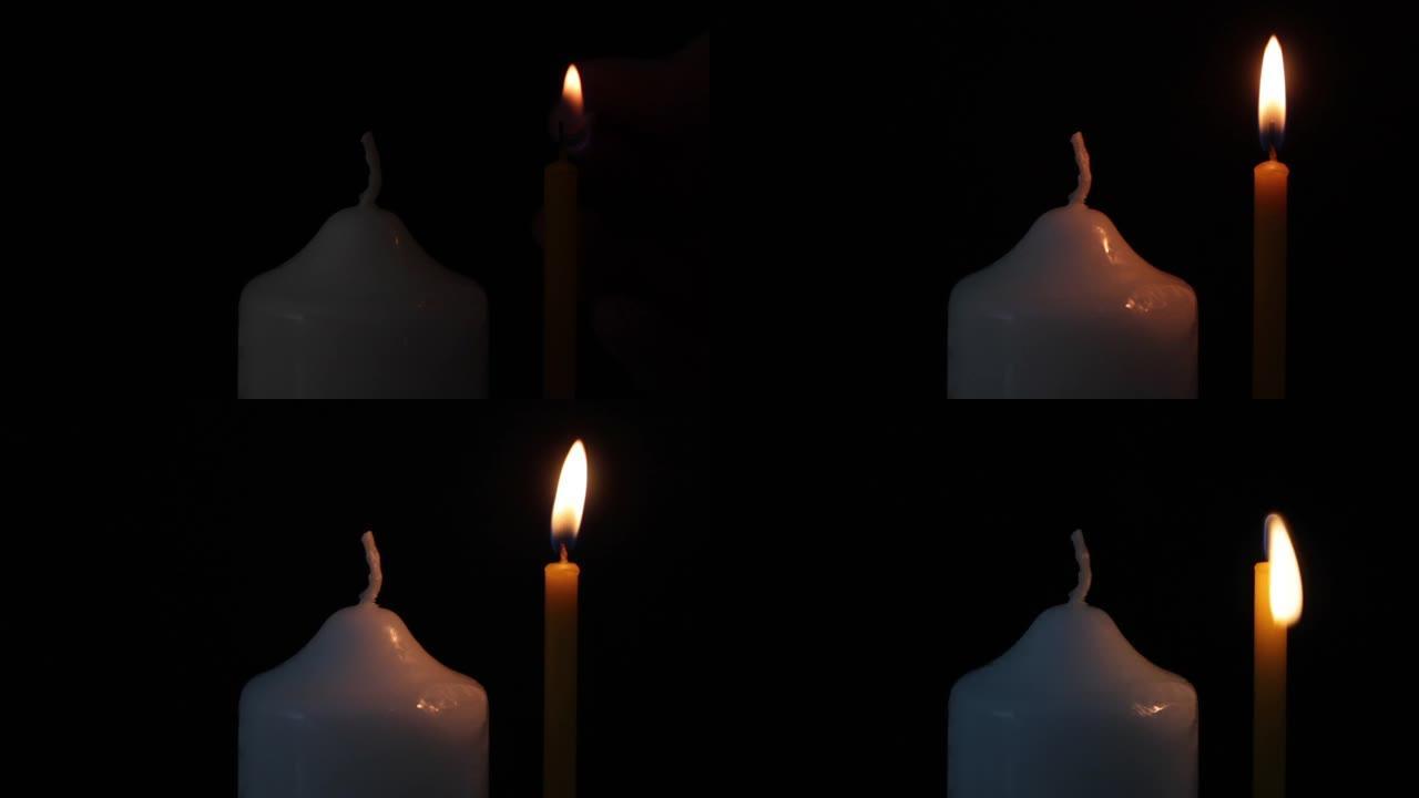 黑色背景上有火柴的男性手点燃蜡烛。特写