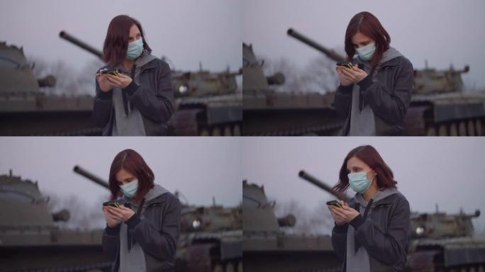 戴着医用防护面具的年轻女子在冠状病毒新型冠状病毒肺炎大流行期间站在军用机器旁，害怕环顾四周。检疫紧急