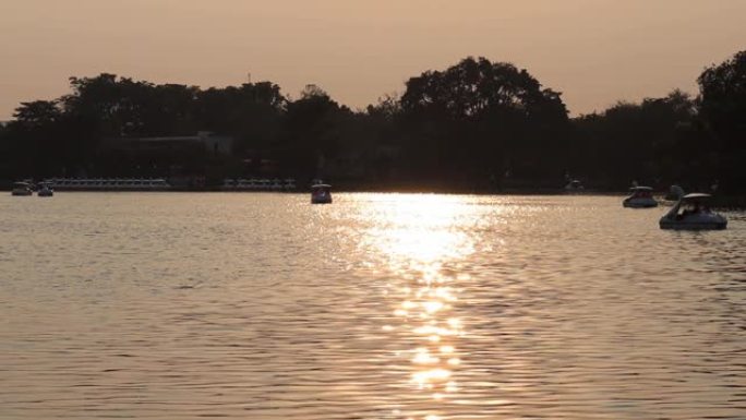 漂浮在湖中的船的轮廓和日出时的倒影。