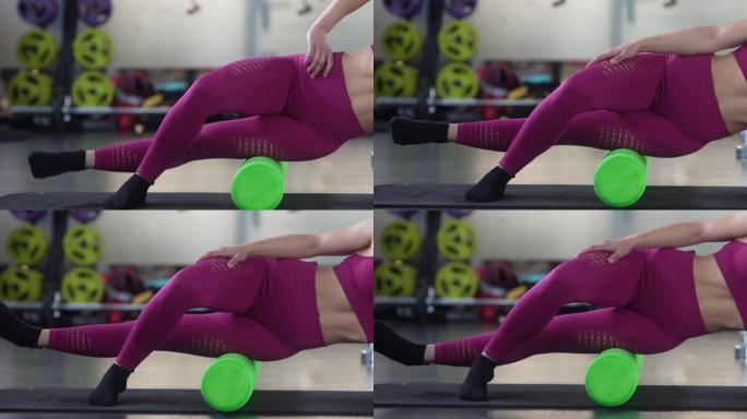 女人用绿色泡沫滚轮放松腿部肌肉