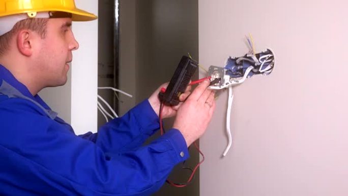 男电工用专用设备检查插座。戴头盔的人