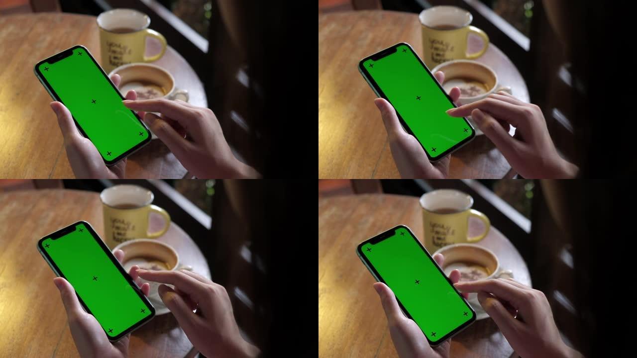 女人在咖啡休息时使用绿屏智能手机。