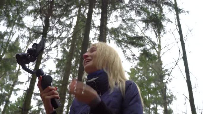 年轻的女孩博客用她的手机和云台制作视频，在大自然的森林。