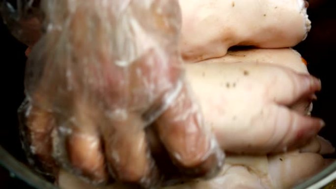 戴着手套的人的手将生猪腿放在金属烹饪锅中，然后倒入清水进行煮沸。