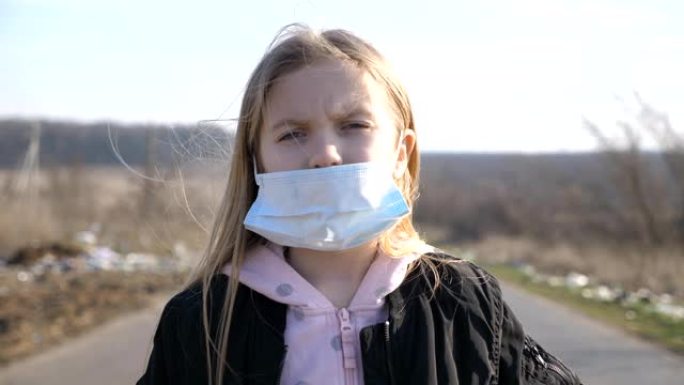 站在户外的戴着医用口罩的小女孩的肖像。悲伤的女性儿童从外面病毒戴着防护面具。冠状病毒和流行病的健康和