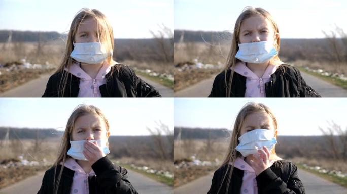 站在户外的戴着医用口罩的小女孩的肖像。悲伤的女性儿童从外面病毒戴着防护面具。冠状病毒和流行病的健康和
