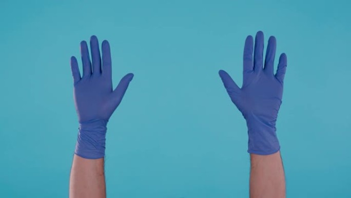 男性手与蓝色手术乳胶手套摩擦手拍手并指向空气隔离在蓝色背景