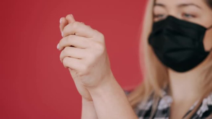 戴着一次性口罩的女人在手上摩擦防腐剂