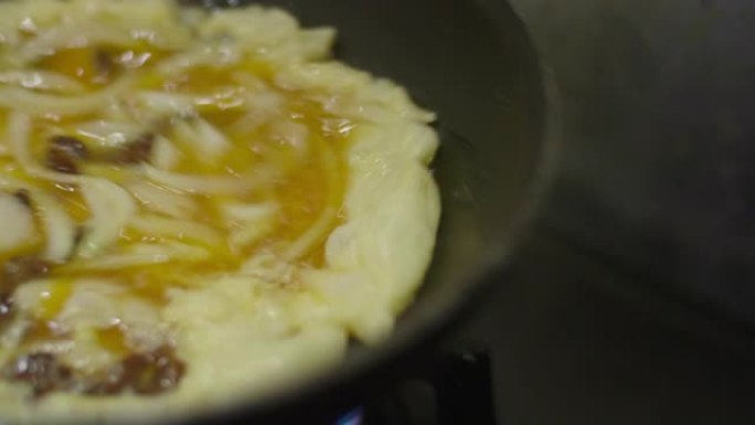 在家用平底锅调味洋葱和西红柿煎蛋卷作为早餐。