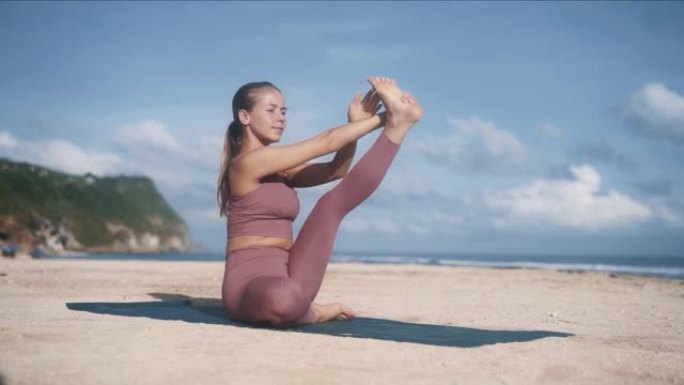 穿着运动服的女孩通过做瑜伽姿势伸展左腿