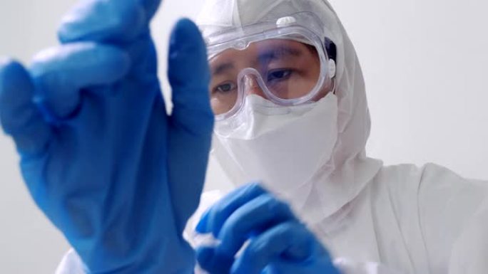 穿着防护危险品PPE套装的亚洲医生戴着医用乳胶手套，慢动作镜头
