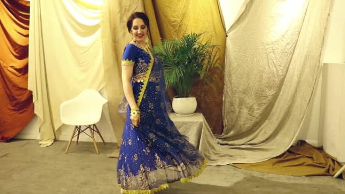 印度女人角色扮演。穿着蓝色印度纱丽连衣裙特写的年轻美女在跳舞。高清