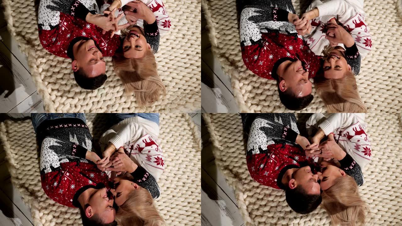 一对恋爱中的圣诞毛衣夫妇躺在针织毯子上的地板上。